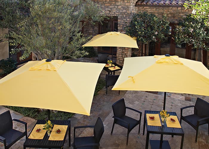 Yellow commercial square market umbrellas in the center of restaurant tables